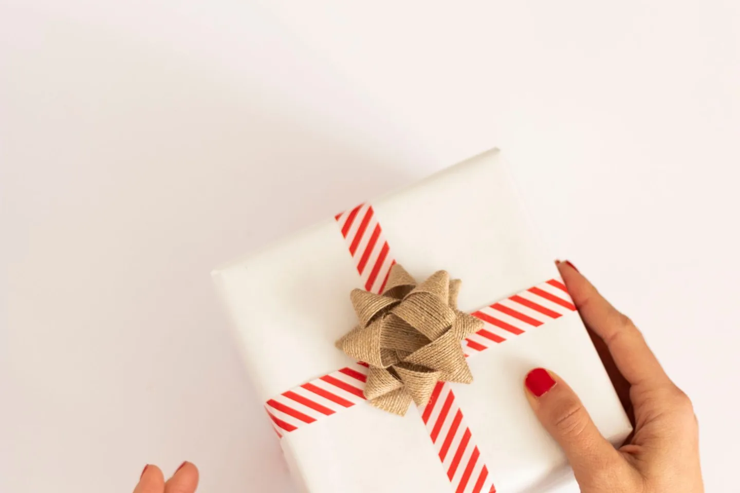 Manos entregando un regalo envuelto con una cinta roja
